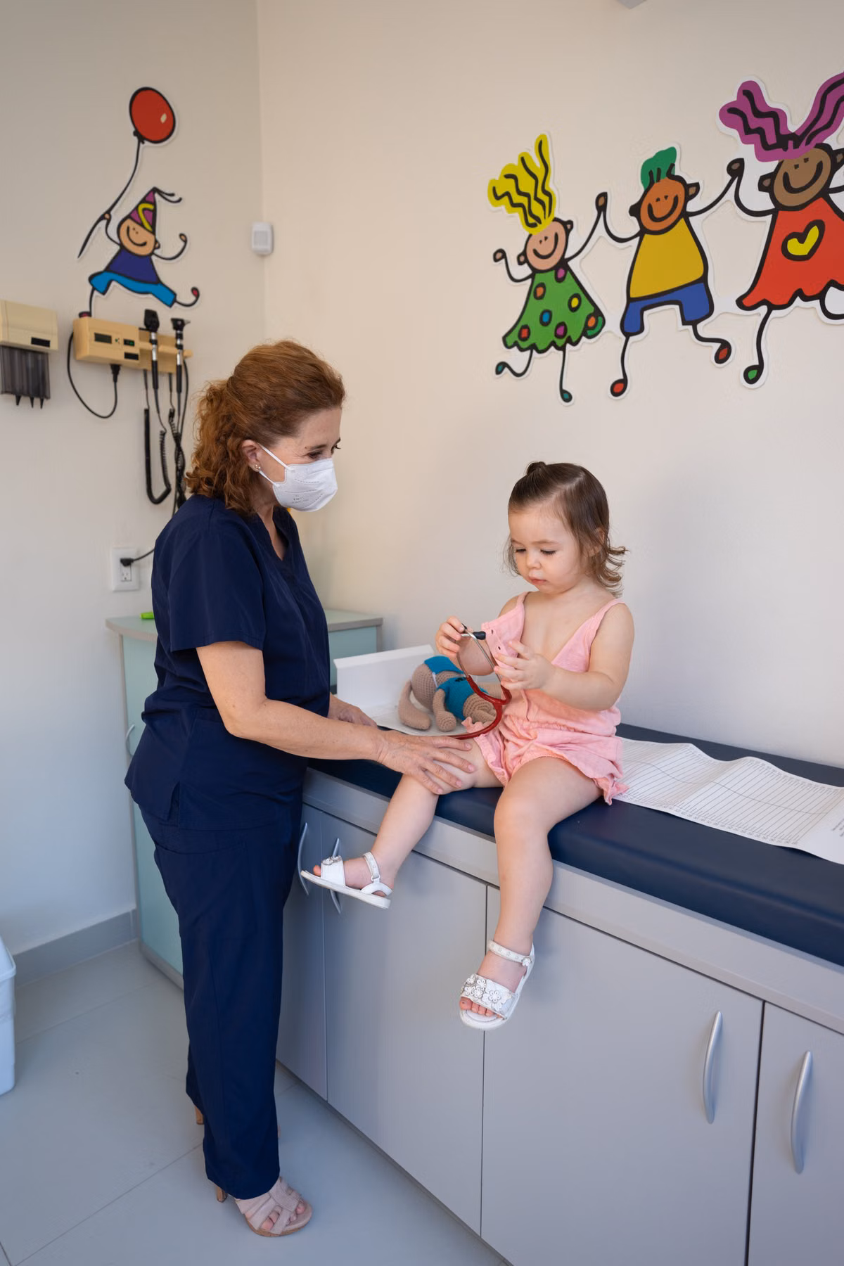 Pediatric nurse examining a young child during a family visit